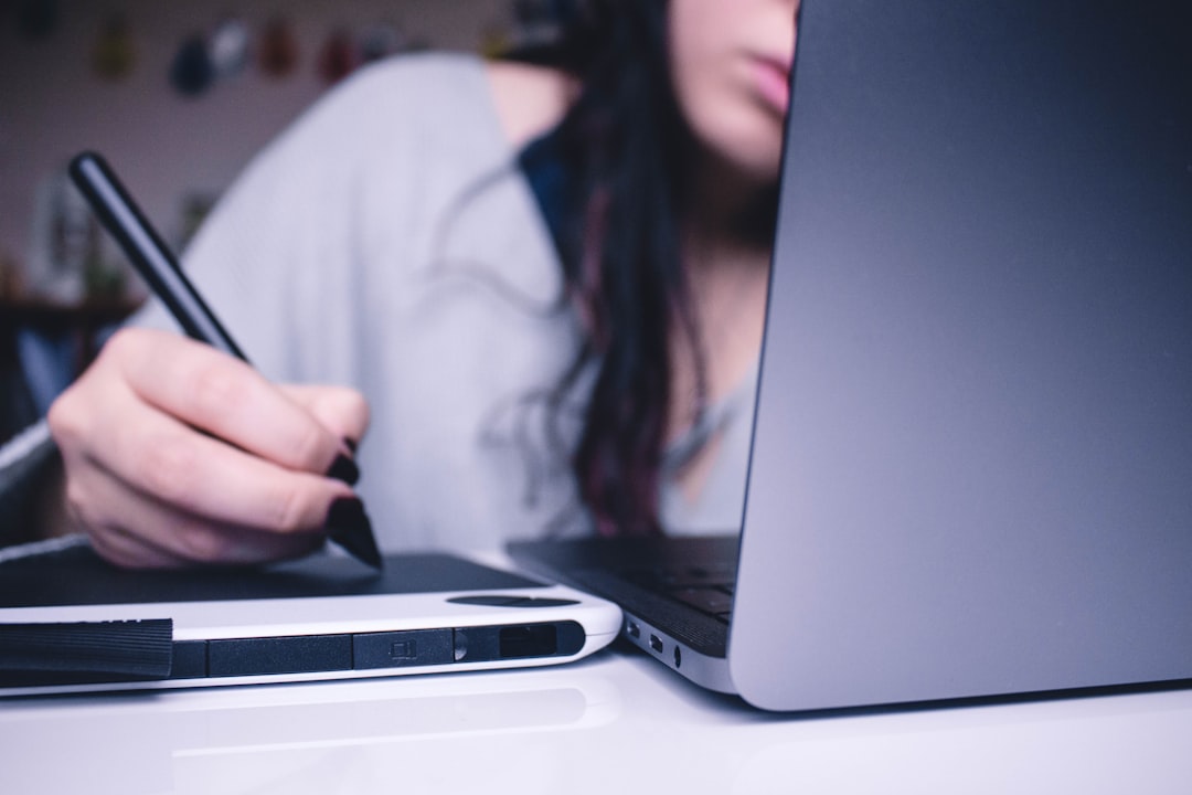 Photo by Josefa nDiaz woman using drawing pad while sitting in front of laptop