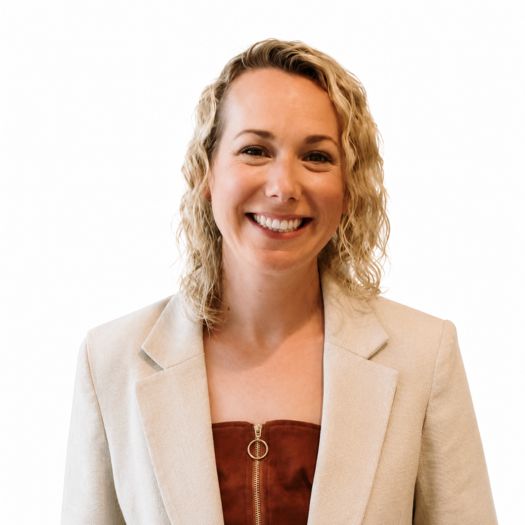 Smiling woman with curly blonde hair in a beige blazer and rust-colored zip-top, posing against a white background.