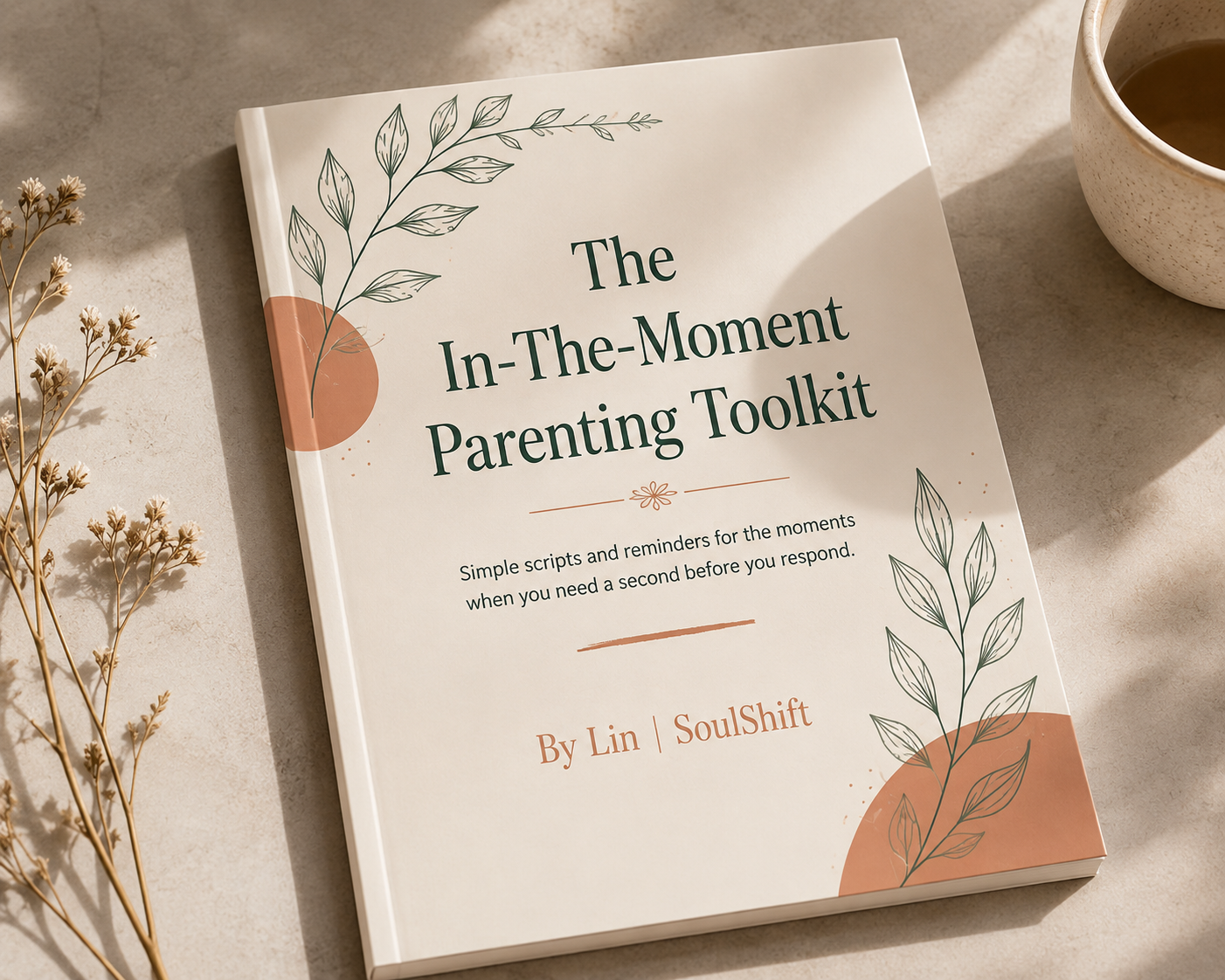 Book titled 'The In-The-Moment Parenting Toolkit' on a neutral tabletop with botanical illustrations and a cup nearby, conveying a calm, practical guide.